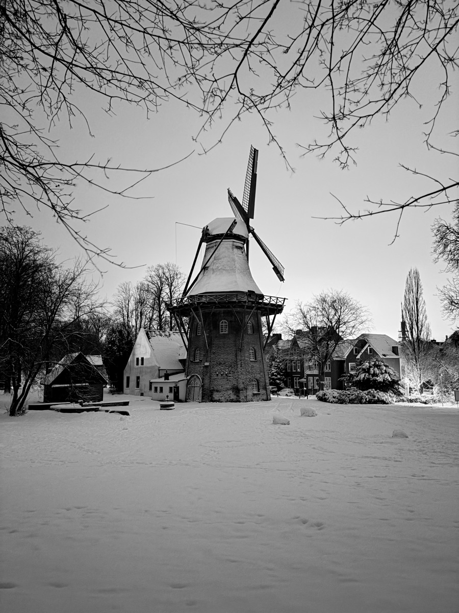 Die verschneite Mühle vor hellem Winterhimmel